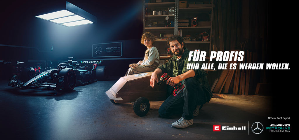 A father and child in a workshop with a homemade soapbox car. In the background, a Mercedes-AMG PETRONAS Formula One car and Einhell tools. Text on the right reads: "For professionals and those who want to become one."