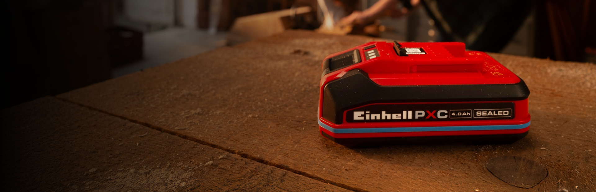 Einhell Power X-Change 4.0Ah SEALEAD battery on a wooden workbench, showing blue ring and label.