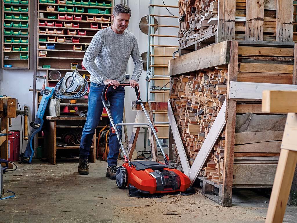 A man sweeps the workshop with a sweeper