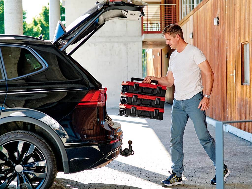 A man puts a toolbox in the car trunk