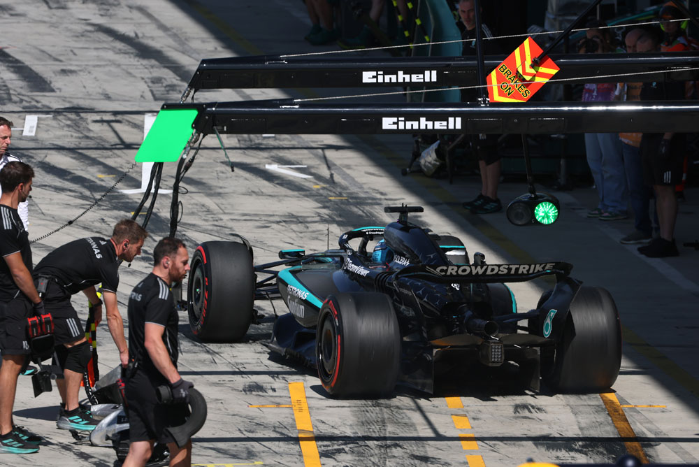 Ein Mercedes-AMG PETRONAS Formula One Wagen steht während eines Boxenstopps in der Boxengasse. Mehrere Teammitglieder sind um das Auto herum. Das Einhell-Branding ist über dem Boxenbereich sichtbar.