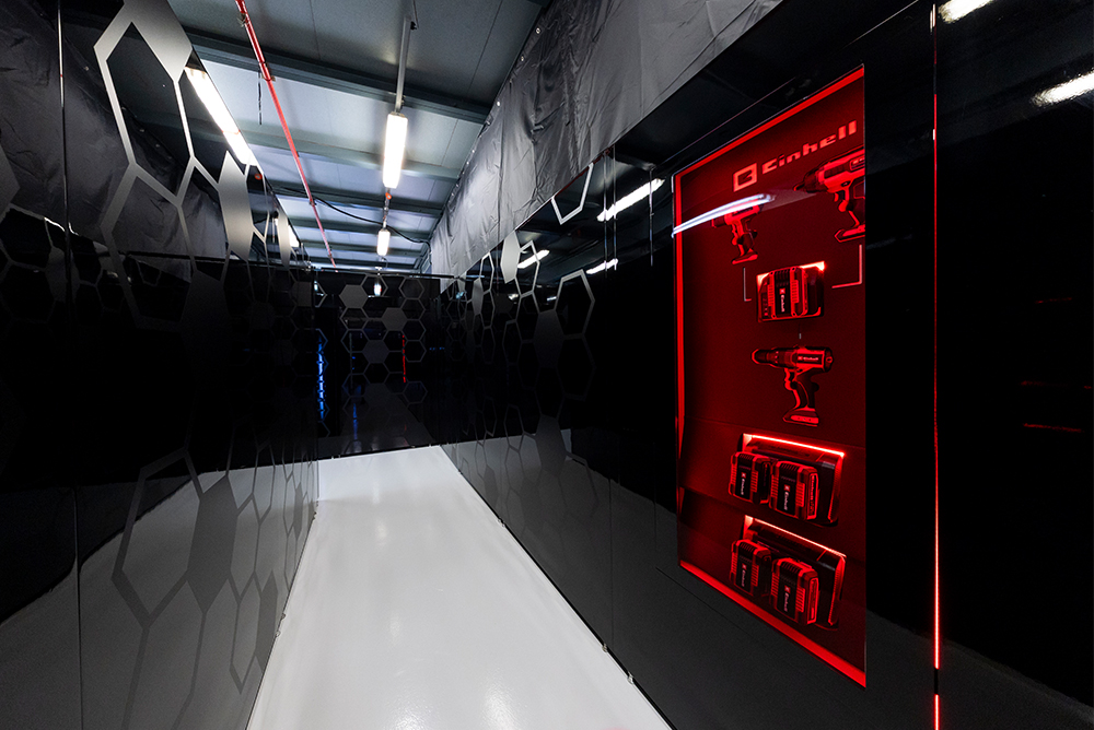 Gang in der Formel-1-Garage in der Boxengasse mit roter Beleuchtung.