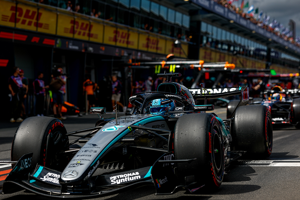 Formel-1-Rennwagen in der Boxengasse, umgeben vom Team vor dem Start.