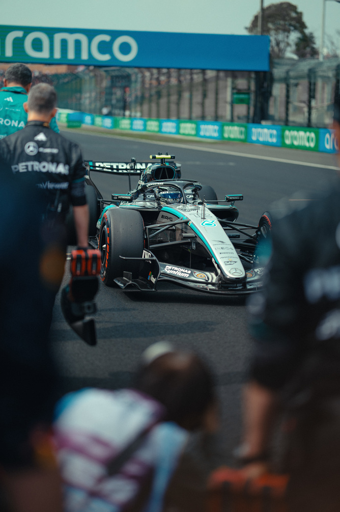 Vůz Mercedes F1 v boxech obklopen týmem