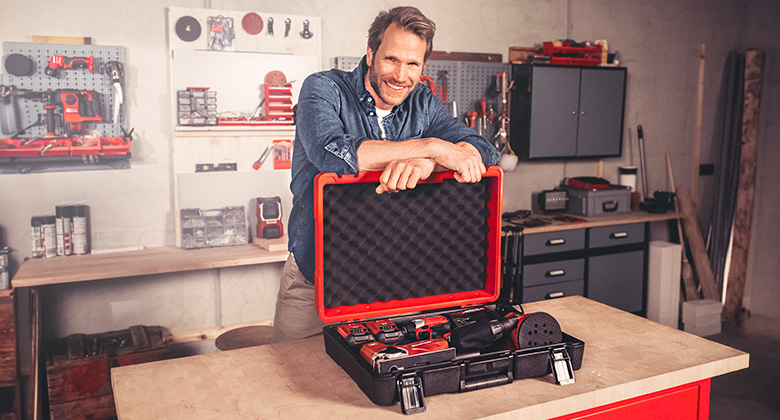 Ein Mann präsentiert eine geöffneten Einhell E-Box in einer Werkstatt.