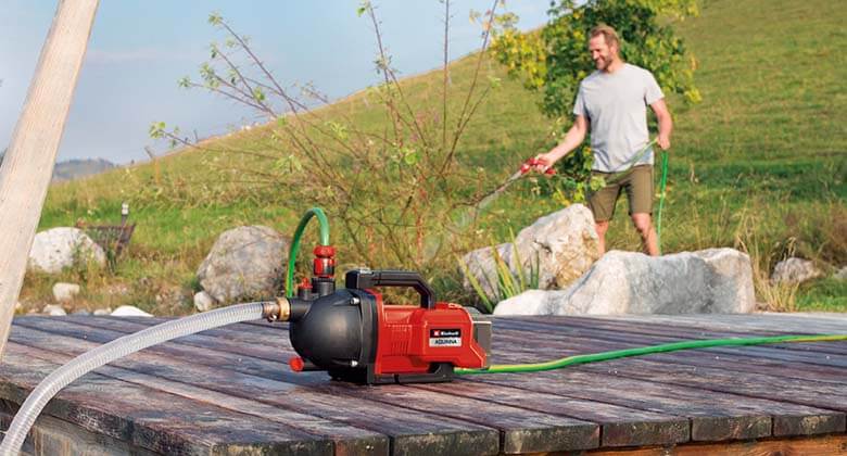 a man watering flowers with the water from a water pump