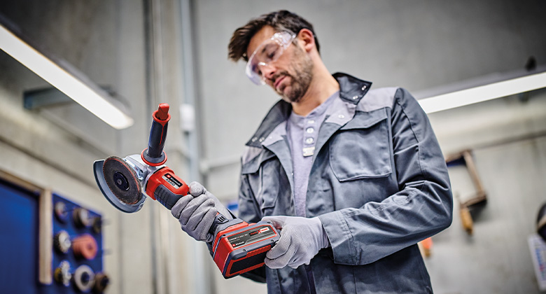 Ein Mann inspiziert einen akkubetriebenen Winkelschleifer in der Werkstatt.